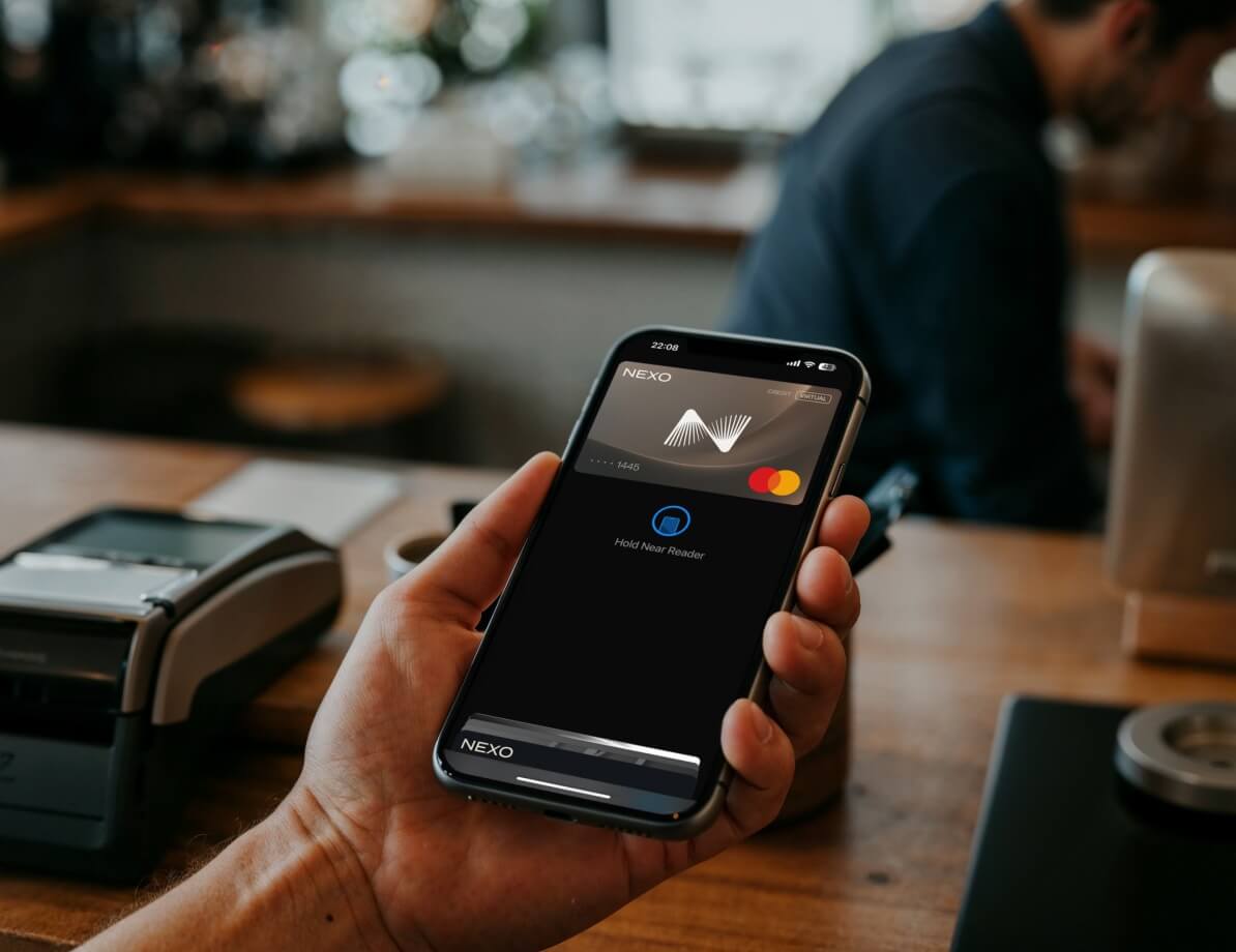 A man holds a phone, activating a virtual card in front of a payment terminal