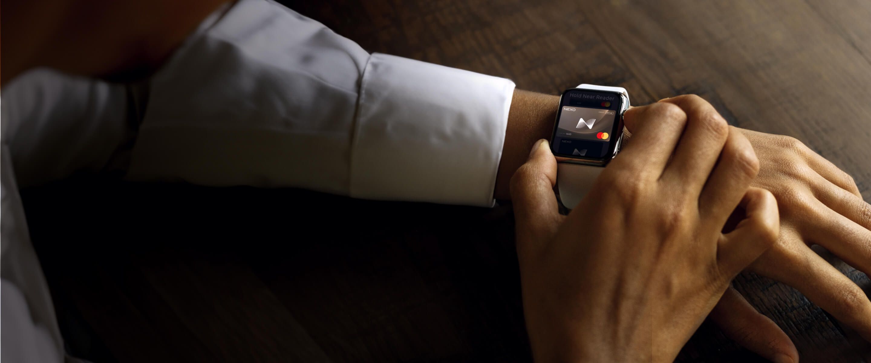 A man wearing a smartwatch on his left wrist activates a virtual card on the device's screen, using his other hand to interact with the display.