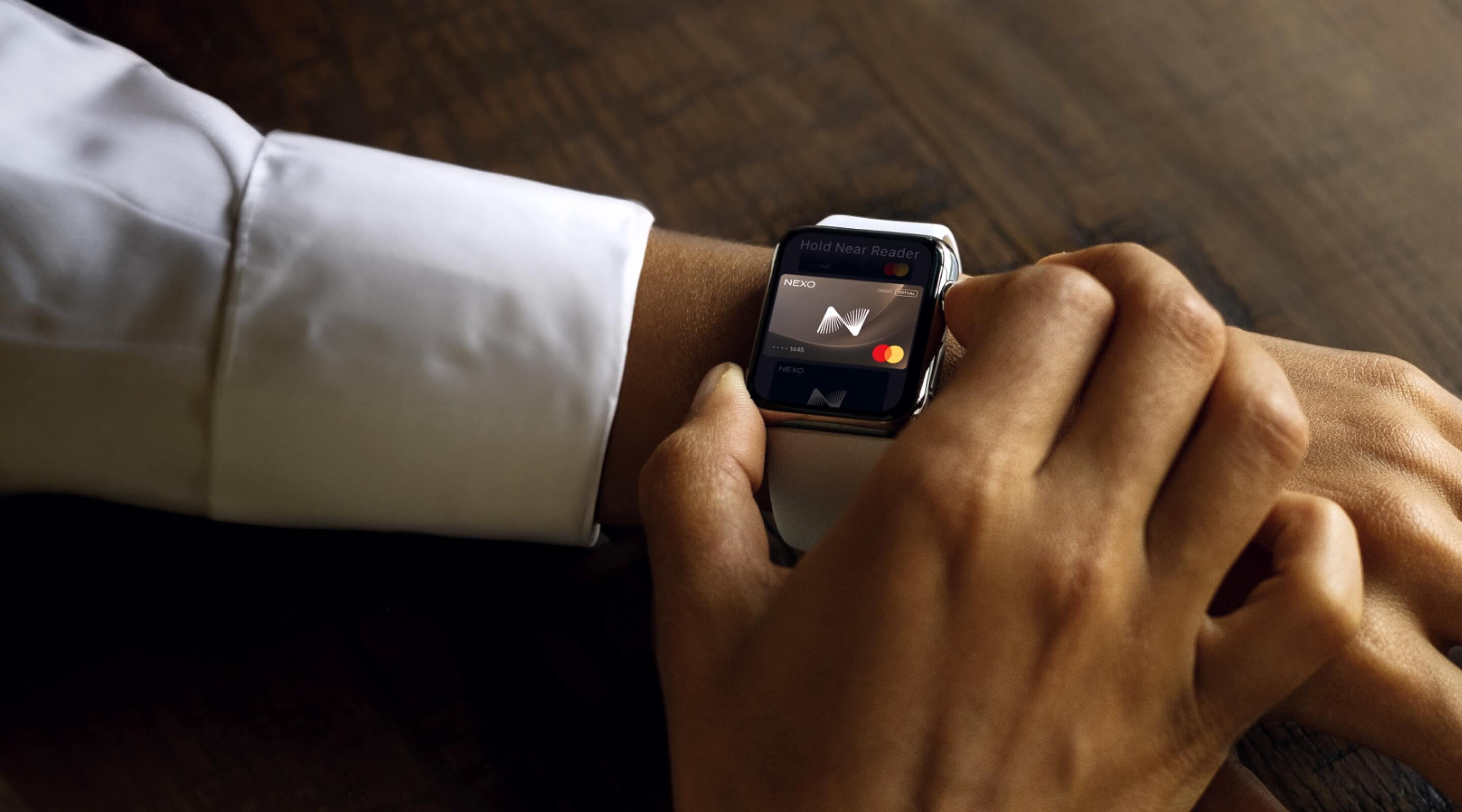 A man wearing a smartwatch on his left wrist activates a virtual card on the device's screen, using his other hand to interact with the display.